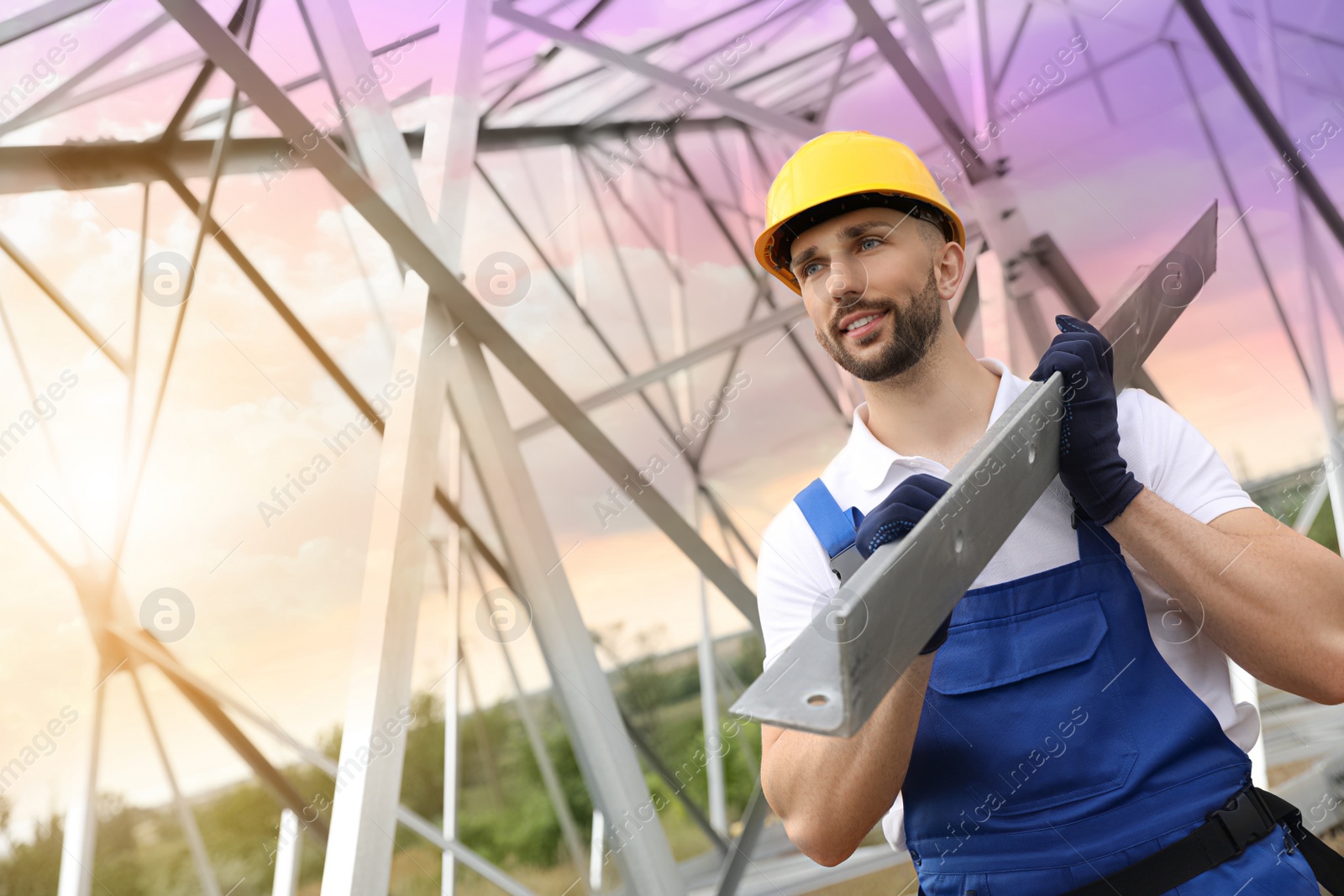 Photo of Worker with detail from high voltage tower construction on building site. Installation of electrical substation