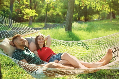 Photo of Young couple resting in comfortable hammock at green garden
