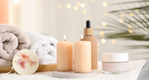 Photo of Spa composition. Burning candles and personal care products on soft surface
