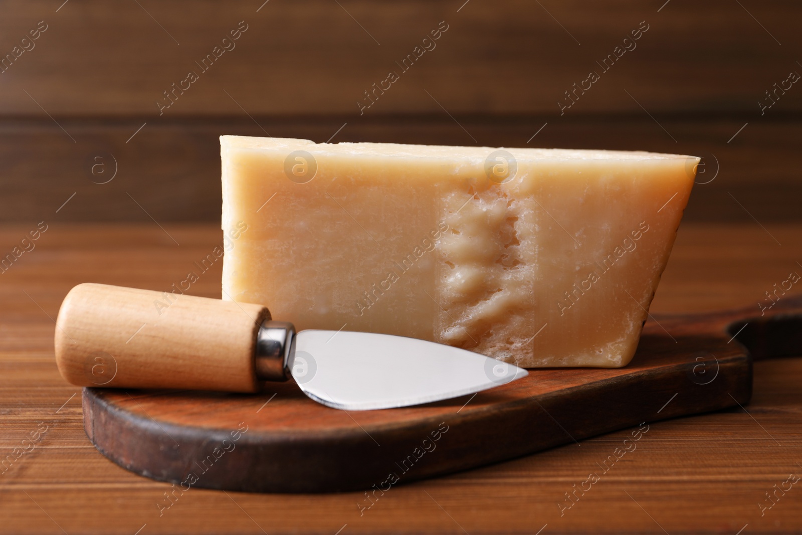 Photo of Delicious parmesan cheese with knife on wooden table