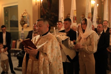 Stryi, Ukraine - September 11, 2022: Priest conducting baptism ceremony in Assumption of Blessed Virgin Mary cathedral