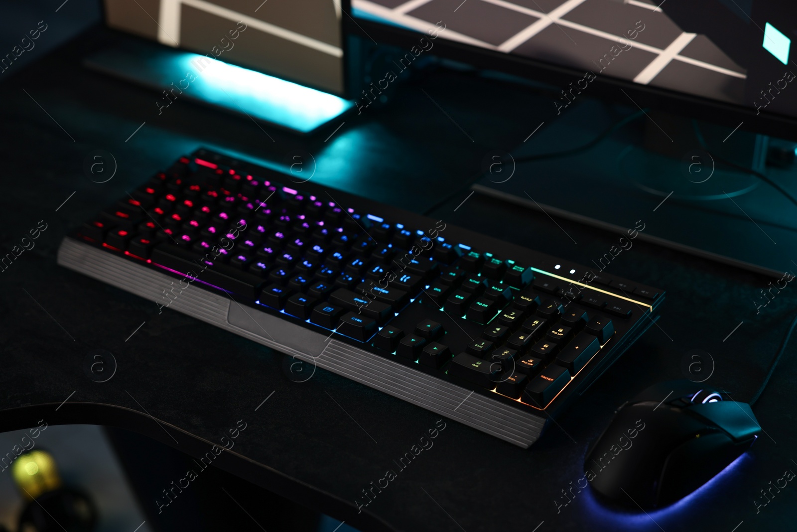 Photo of Playing video games. Computer keyboard with RGB lighting and mouse on table indoors