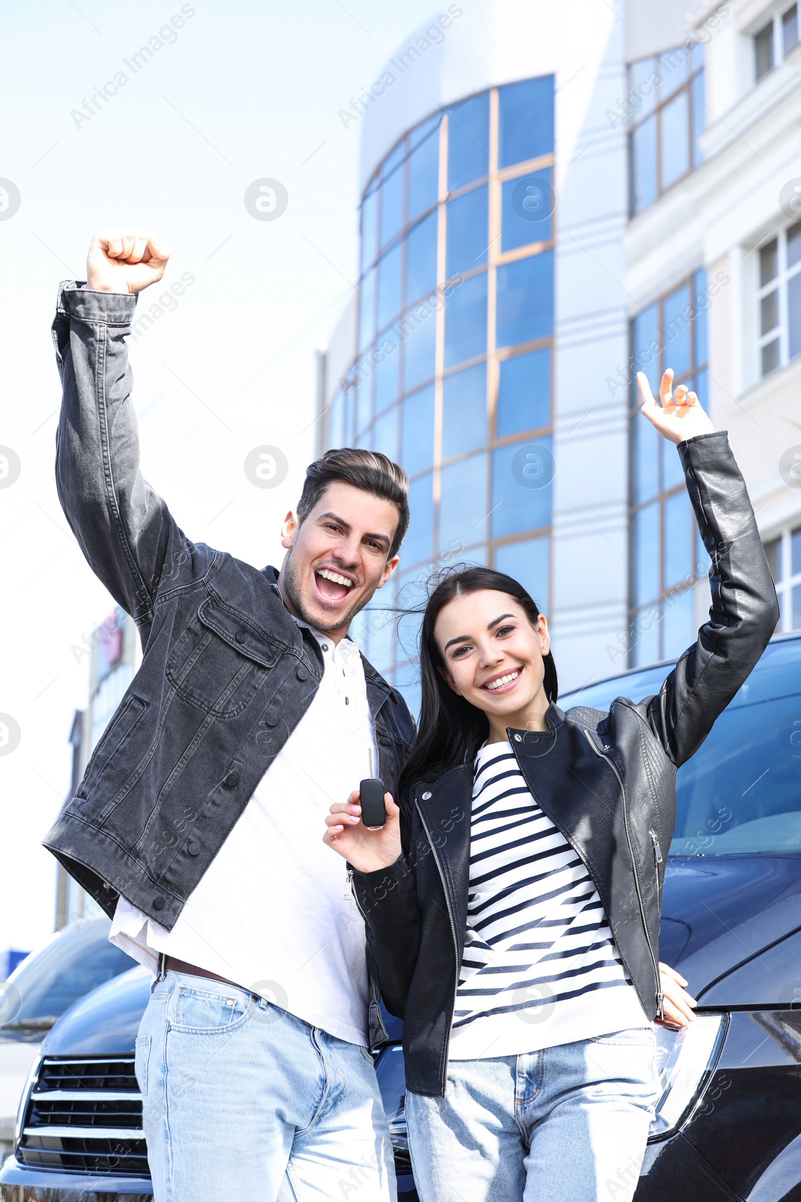 Photo of Happy couple with key near car on city street. Buying new auto