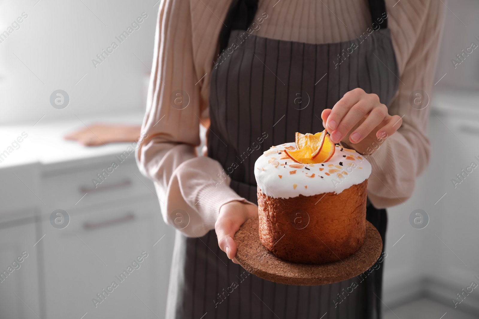 Photo of Young woman with traditional decorated Easter cake in kitchen, closeup. Space for text