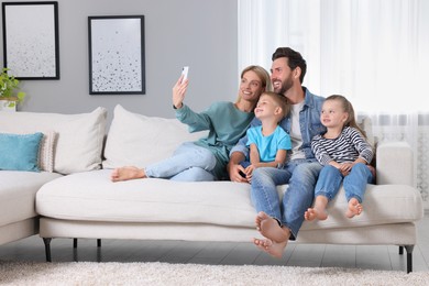 Photo of Happy family taking selfie together on sofa at home