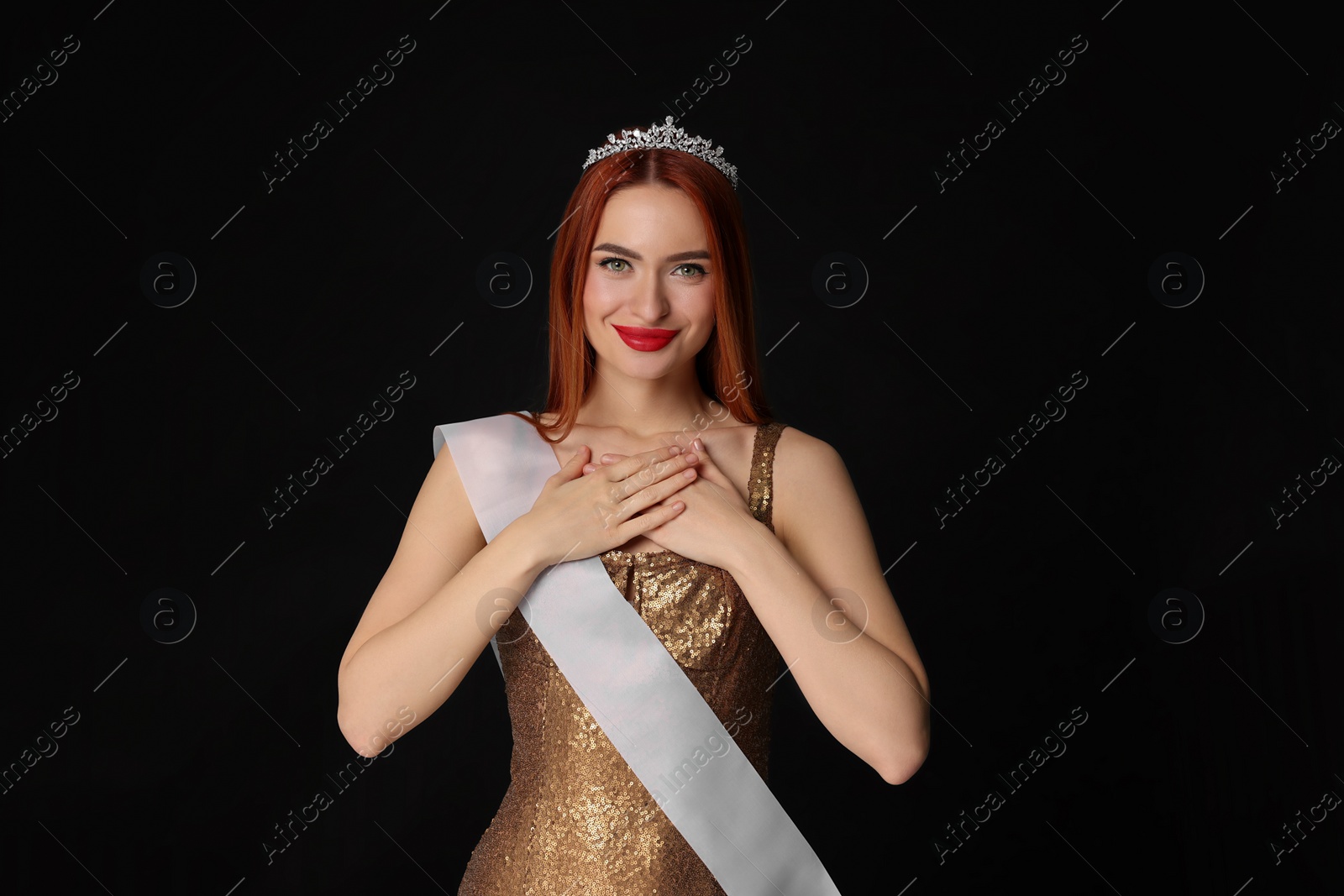 Photo of Beautiful young woman with tiara and ribbon in dress on black background. Beauty contest