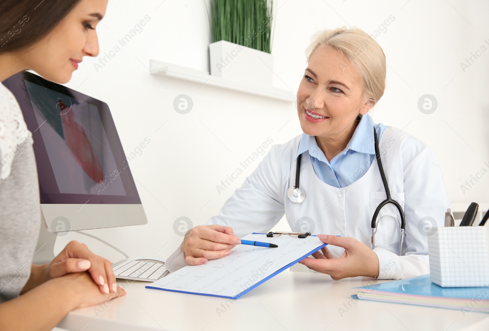 Photo of Female doctor working with patient in clinic. Cardiology consultation