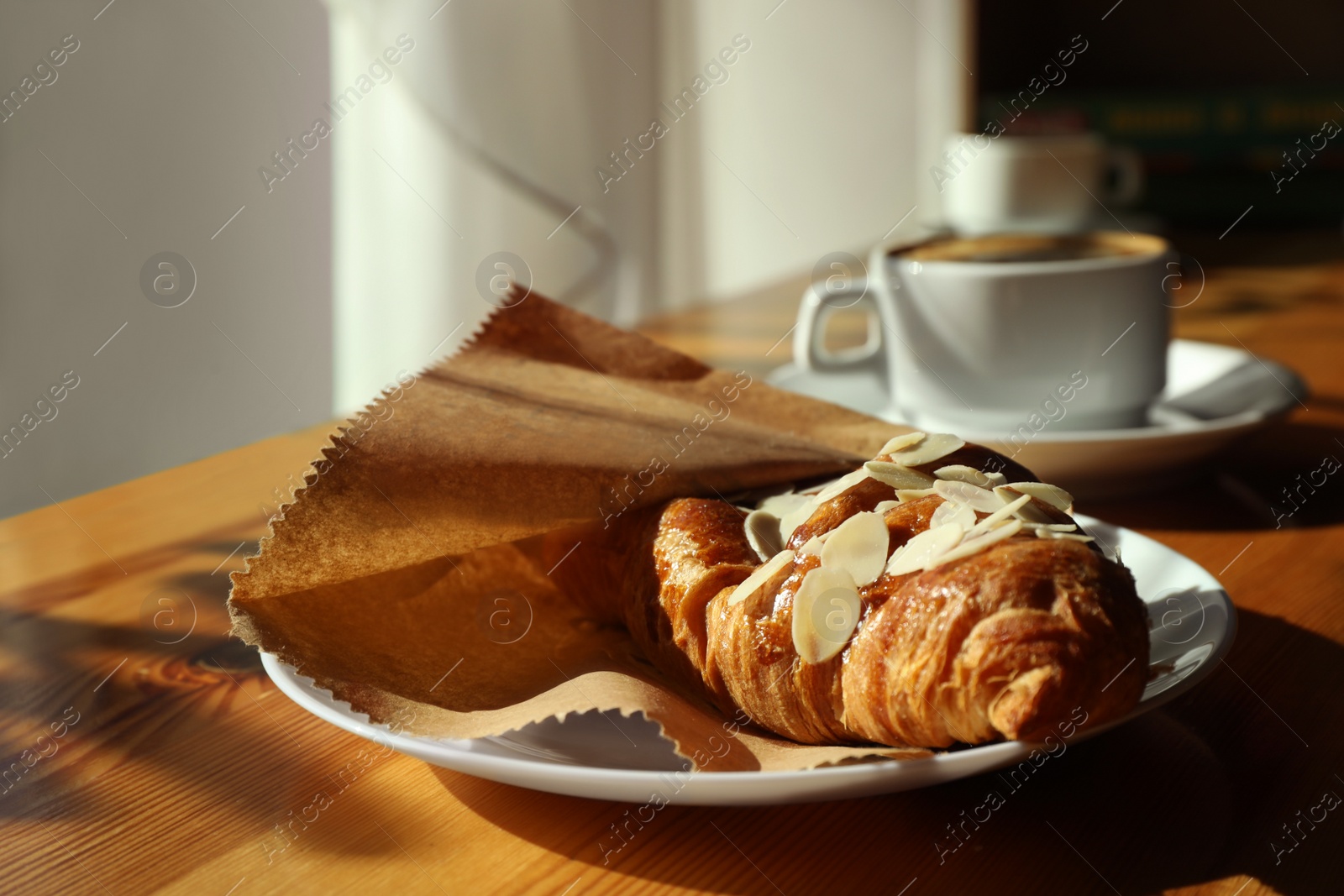 Photo of Cup of fresh aromatic coffee and croissant at table in cafe