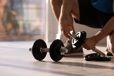 Photo of Male athlete with adjustable dumbbells indoors. Space for text