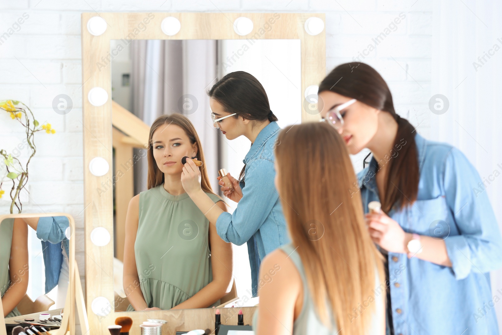 Photo of Professional visage artist applying makeup on woman's face in salon