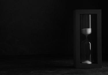 Photo of Sandglass on table against black background, space for text. Pareto principle concept