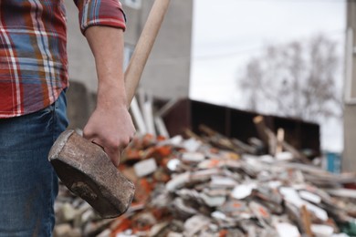 Photo of Man with sledgehammer near pile of broken stones outdoors, closeup. Space for text