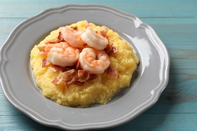 Photo of Plate with fresh tasty shrimps, bacon and grits on light blue wooden table, closeup