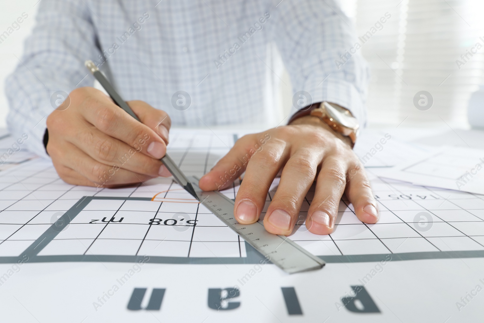 Photo of Architect working with construction drawings indoors, closeup