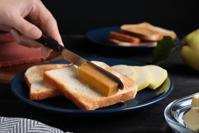 Photo of Woman making sandwich with quince paste at table, closeup