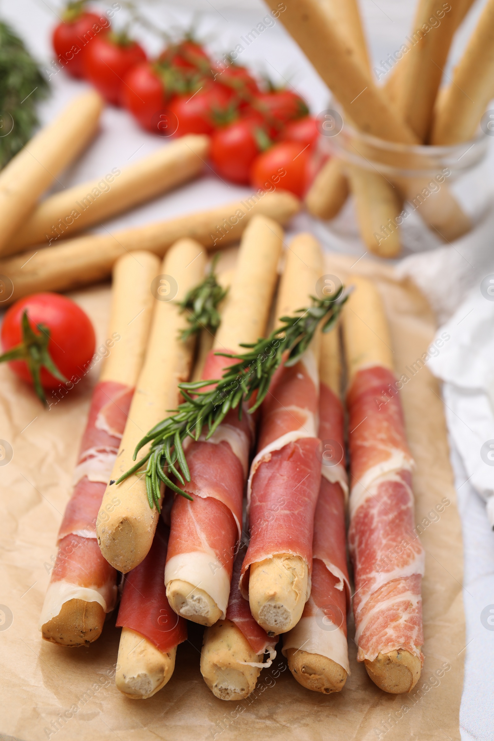 Photo of Delicious grissini sticks with prosciutto on white table