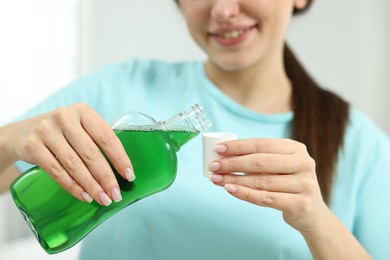 Photo of Young woman using mouthwash on light background, closeup