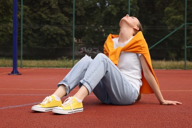 Photo of Woman wearing yellow classic old school sneakers on court outdoors