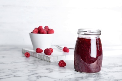 Photo of Jar with delicious raspberry jam on table