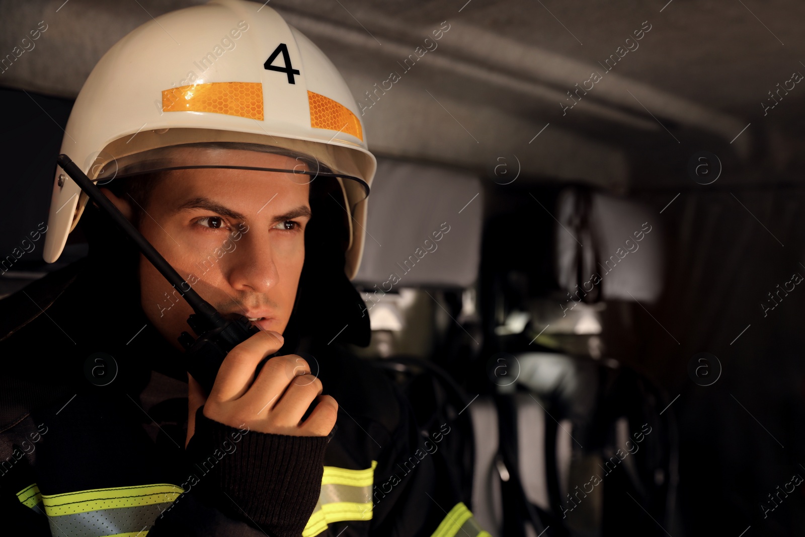 Photo of Firefighter using portable radio set in fire truck, space for text