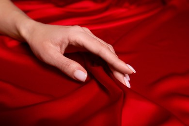 Photo of Woman touching soft red fabric, closeup view
