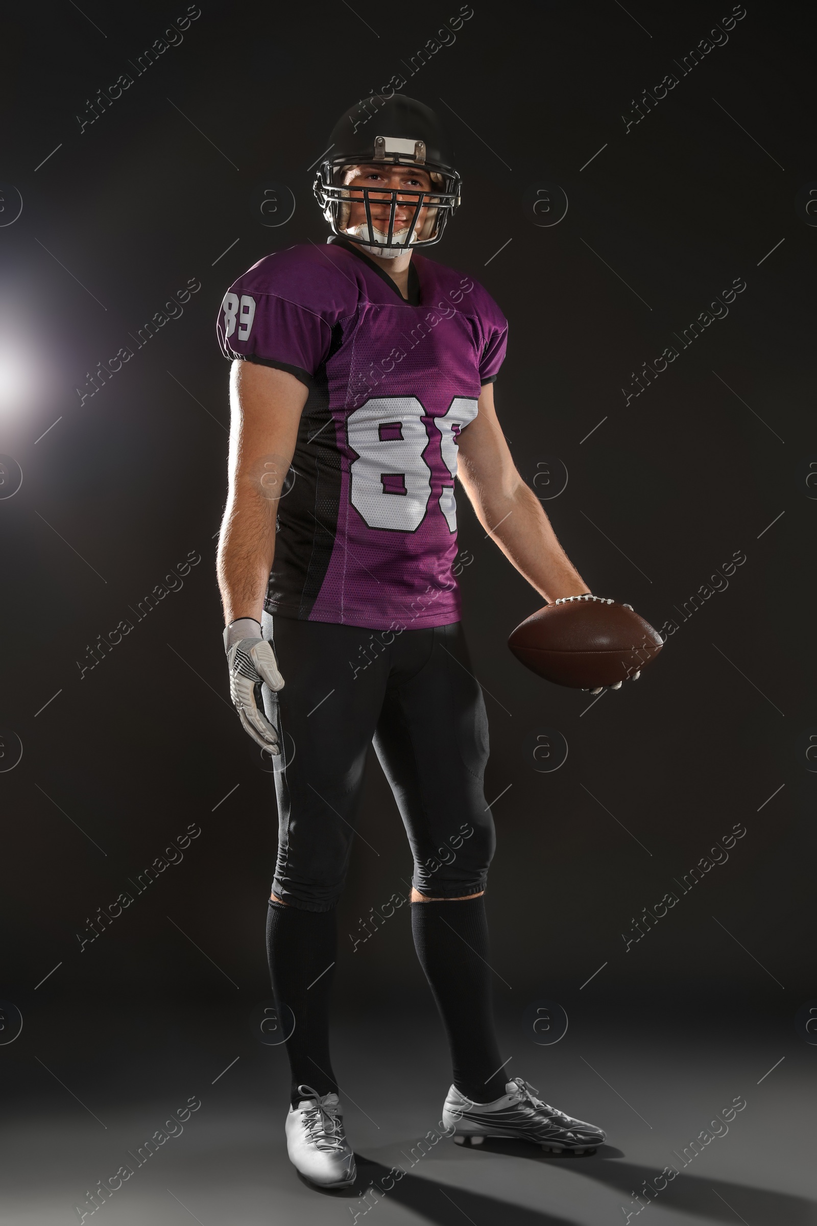 Photo of American football player with ball on dark background