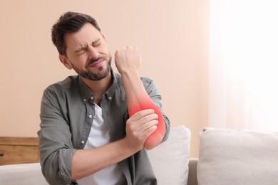 Image of Man suffering from pain in elbow indoors. Space for text