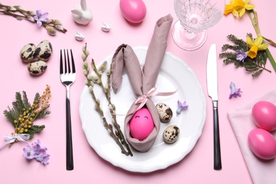 Festive Easter table setting with eggs on pink background, flat lay