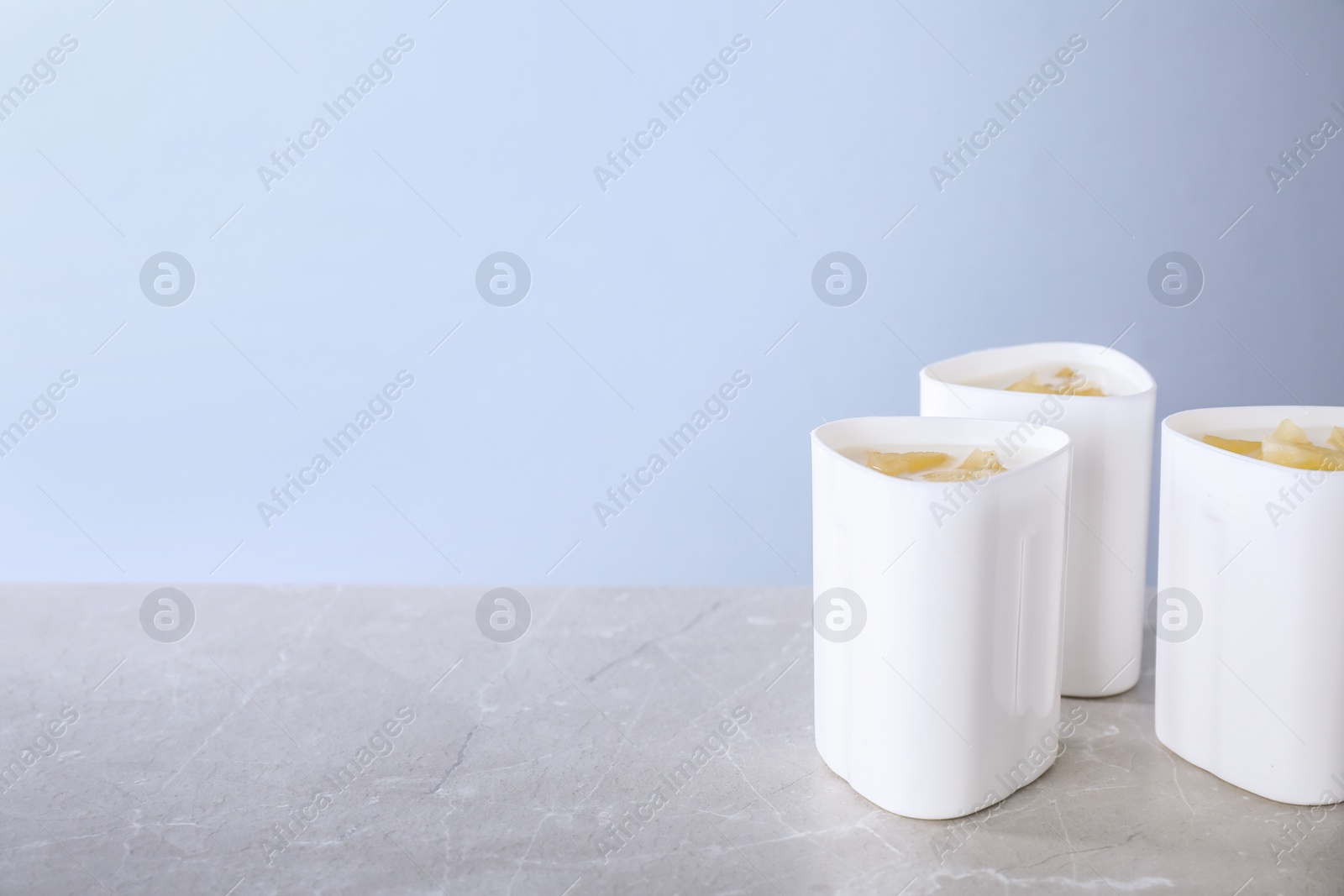 Photo of Cups of yogurt on table against color background, space for text. Multi cooker recipe