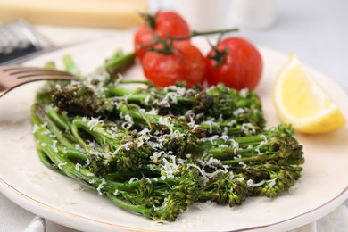Photo of Tasty cooked broccolini with cheese, tomatoes and lemon on plate, closeup