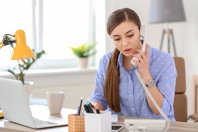 Young woman talking on phone at workplace