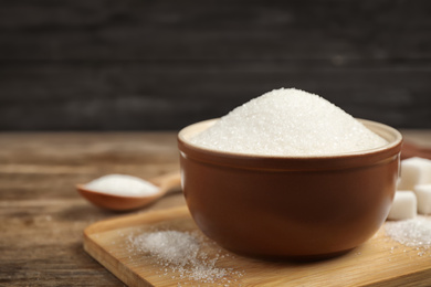 Photo of Granulated sugar in bowl on wooden table