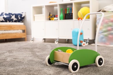 Photo of Toy walker on floor in child's room, space for text. Interior design
