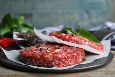 Photo of Raw meat cutlets for burger on wooden table, closeup