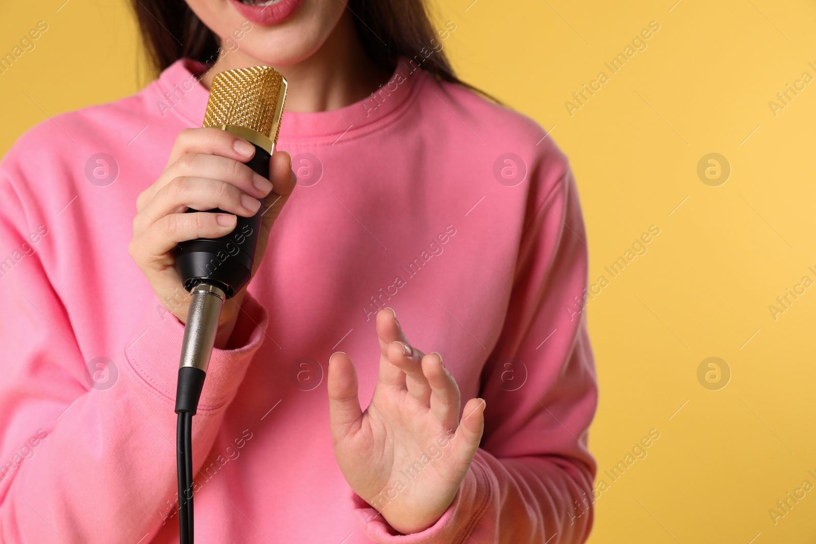 Photo of Young woman singing in microphone on color background, closeup view with space for text