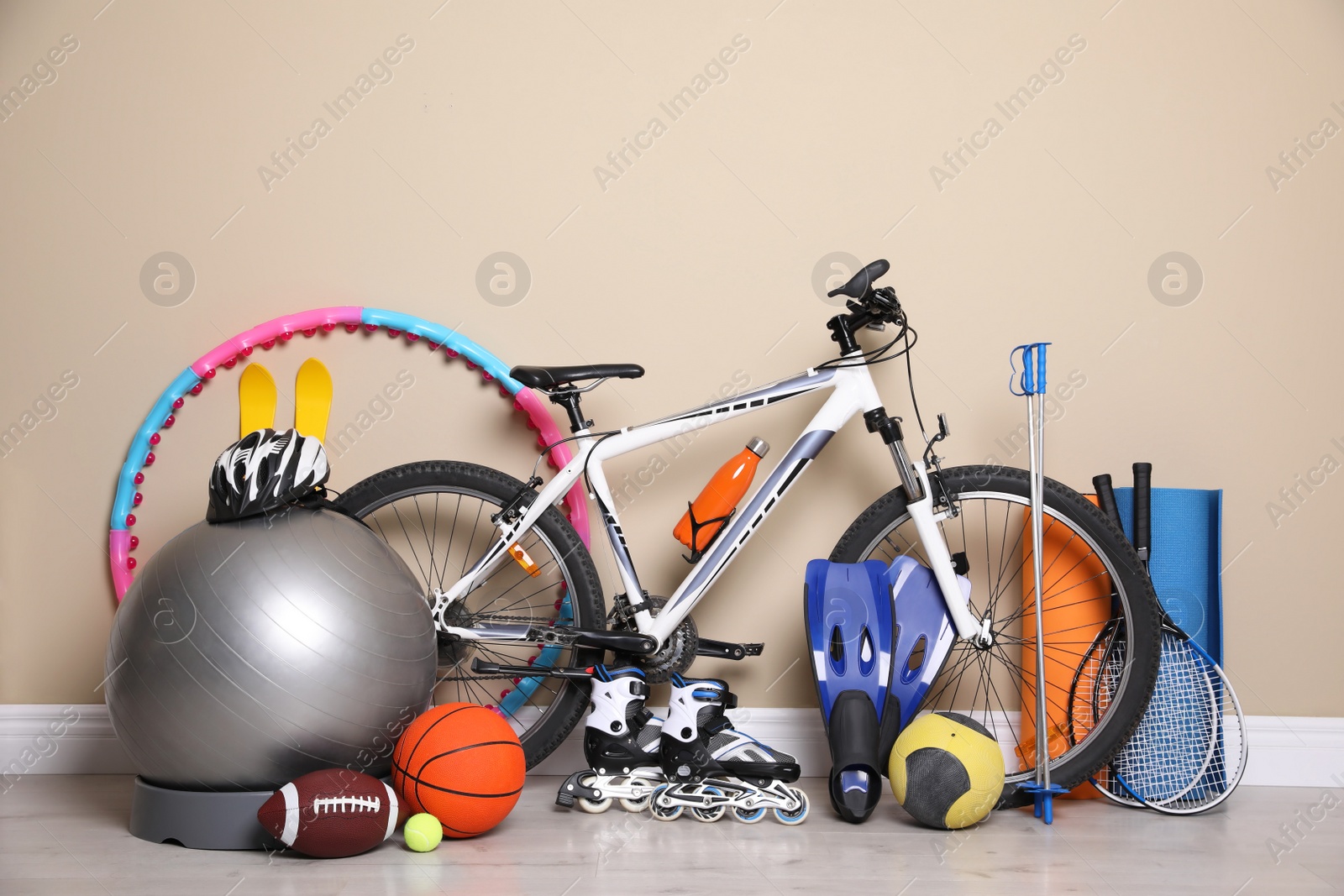 Photo of Bicycle and different modern sport equipment near beige wall