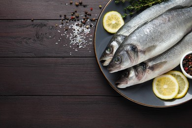 Photo of Tasty sea bass fish with spices on dark wooden table, flat lay. Space for text