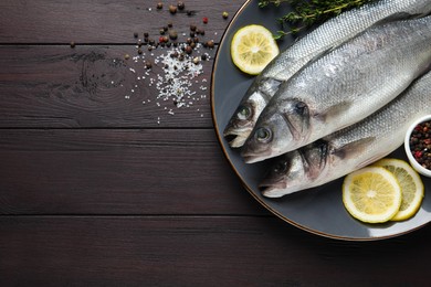 Tasty sea bass fish with spices on dark wooden table, flat lay. Space for text