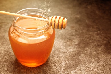 Image of Natural honey in glass jar and dipper under sunlight, closeup. Space for text