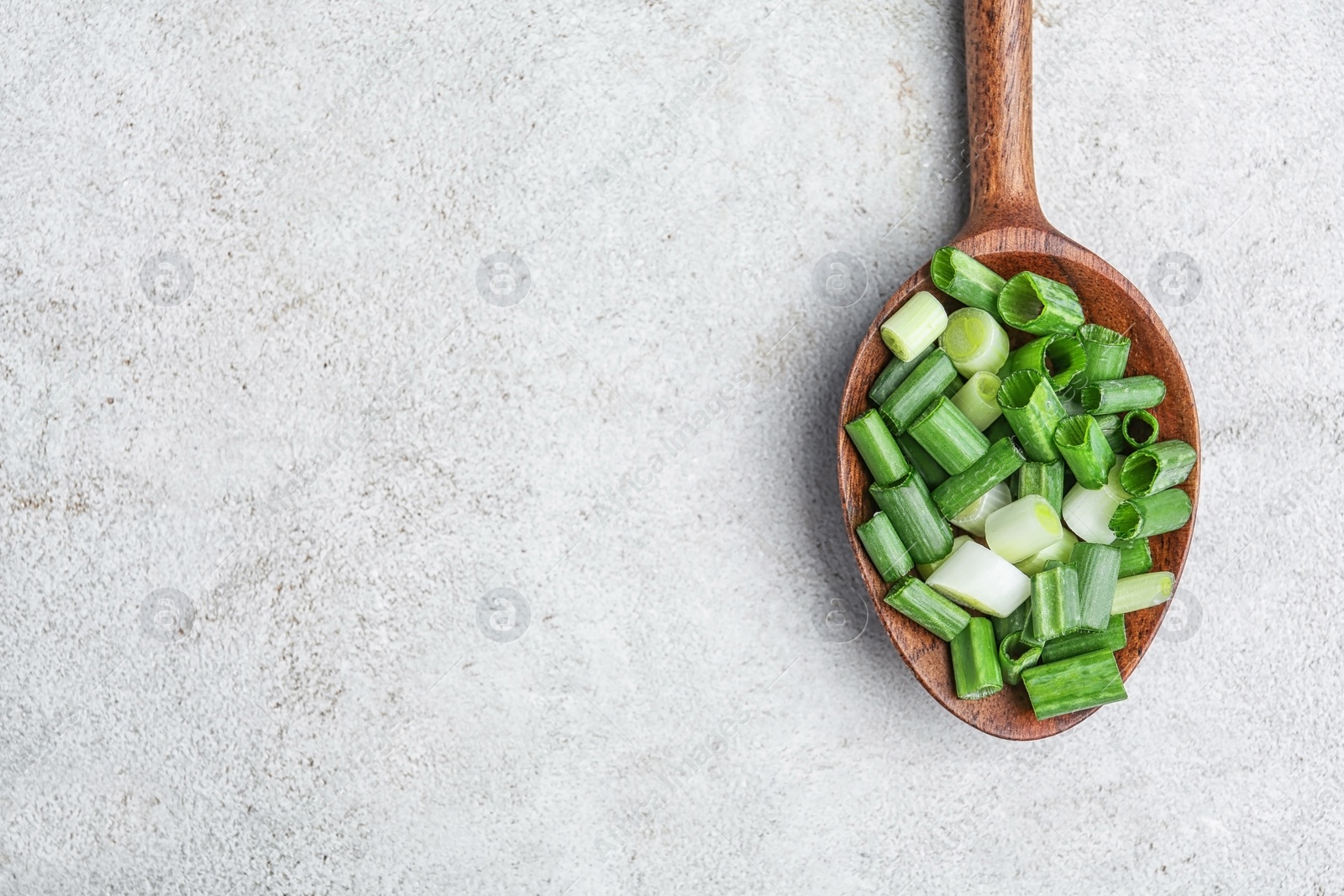 Photo of Spoon with chopped green onion on table, top view