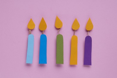 Different paper candles on pink background, flat lay