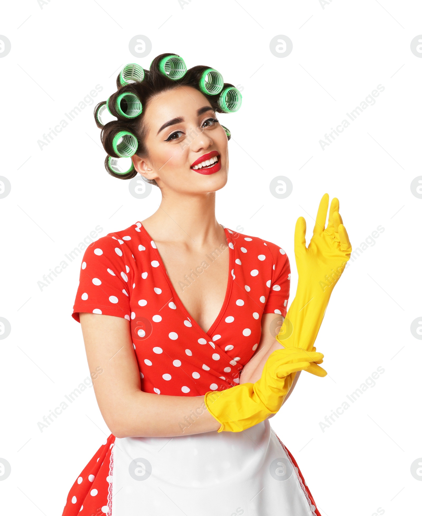 Photo of Funny young housewife with hair rollers putting on rubber gloves against white background