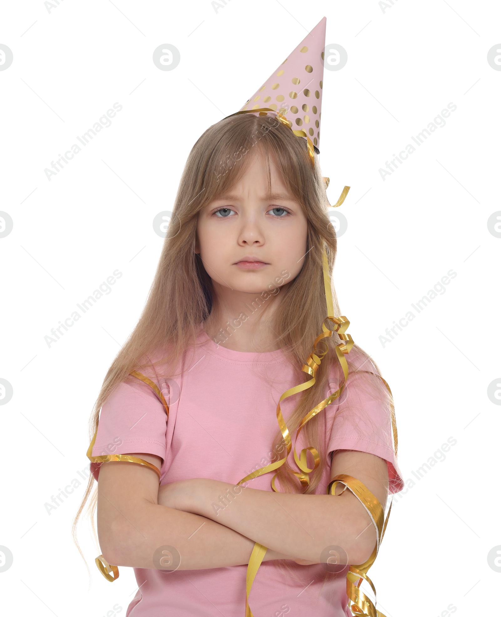 Photo of Unhappy little girl in party hat with crossed arms on white background