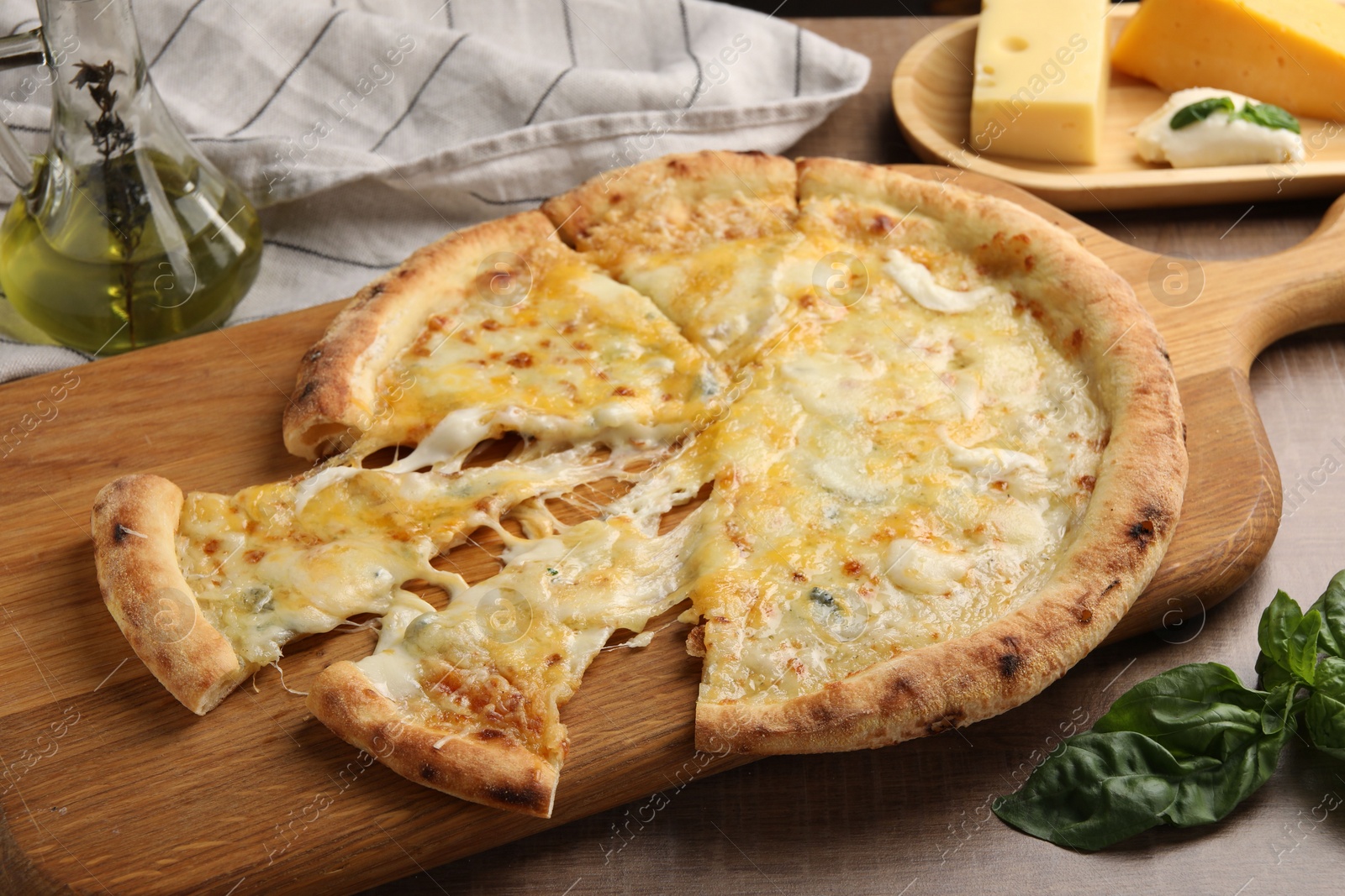 Photo of Delicious cut cheese pizza and ingredients on wooden table