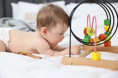 Cute baby boy with toys on bed at home