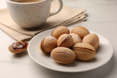 Homemade walnut shaped cookies with boiled condensed milk on white marble table, closeup