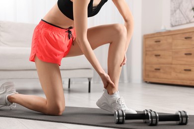 Photo of Woman suffering from leg pain on exercise mat in room, closeup