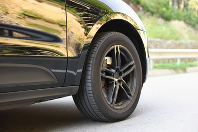 Photo of Modern black car parked on asphalt road outdoors