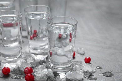 Shots of vodka, cranberries and ice on grey table