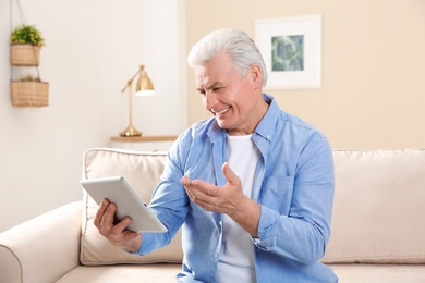 Mature man using video chat on tablet at home